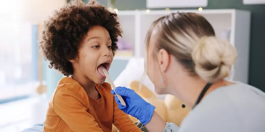 Child being examined by a nurse for strep throat.